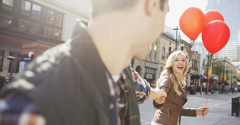 Smiling woman leading man down city street