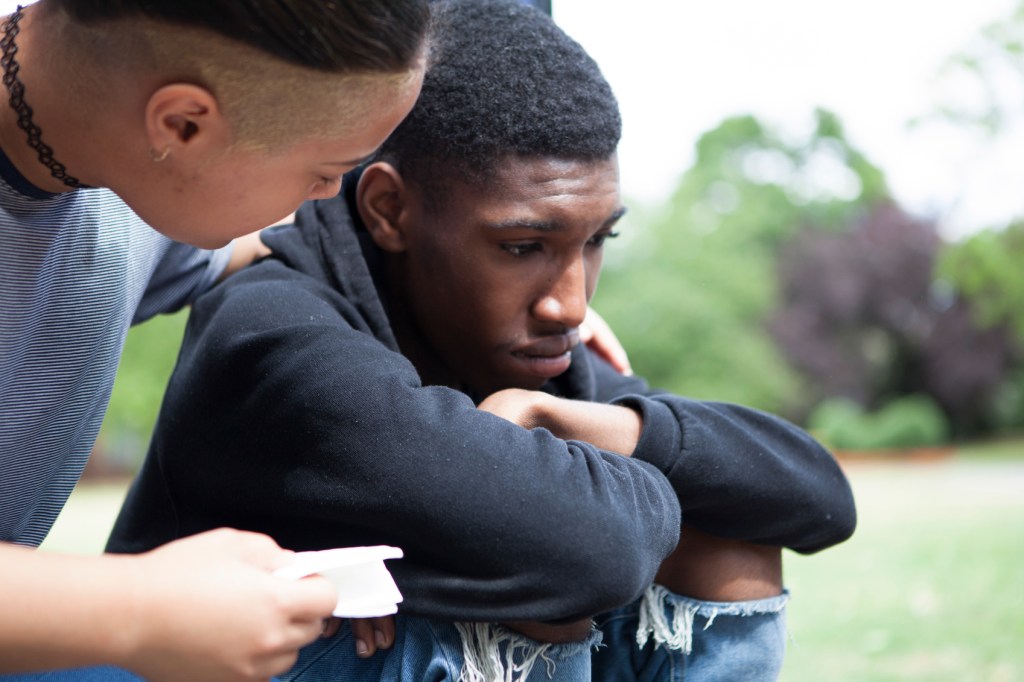 Teenager sitting on the curb crying